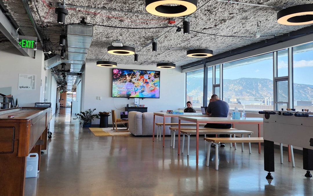 A common space in the Boulder office with a foosball table, community tables to work from, and a view of the mountains.